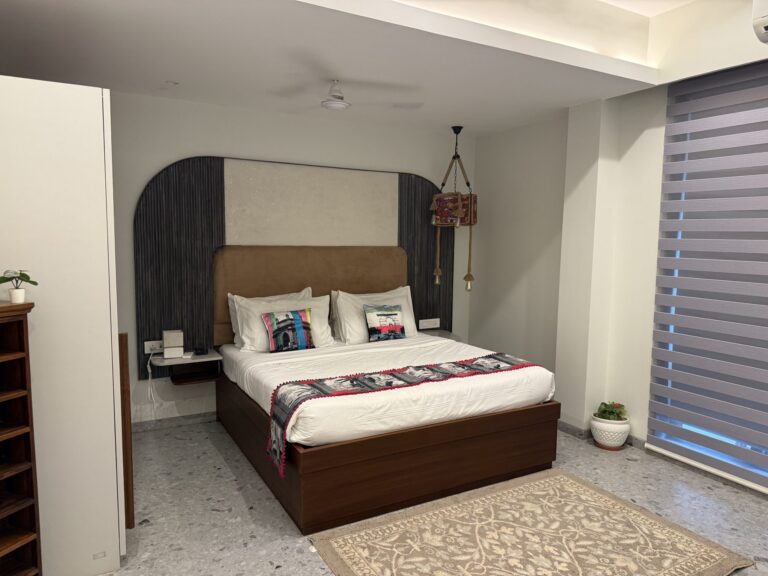 Bright, tidy bedroom with a neatly made bed, pillows and a bedside lamp