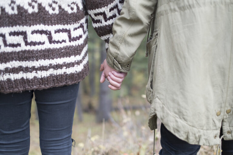 Couple in cozy sweaters holding hands on a quiet autumn walk