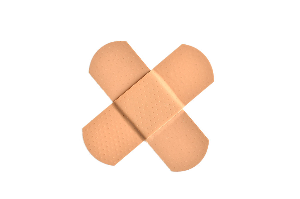 Two adhesive bandages crossed on a clean white background