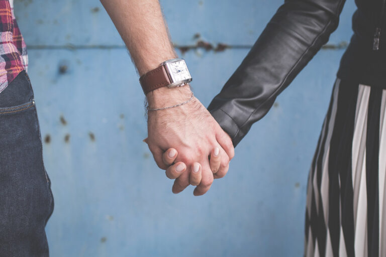 Couple holding hands against a soft blue wall