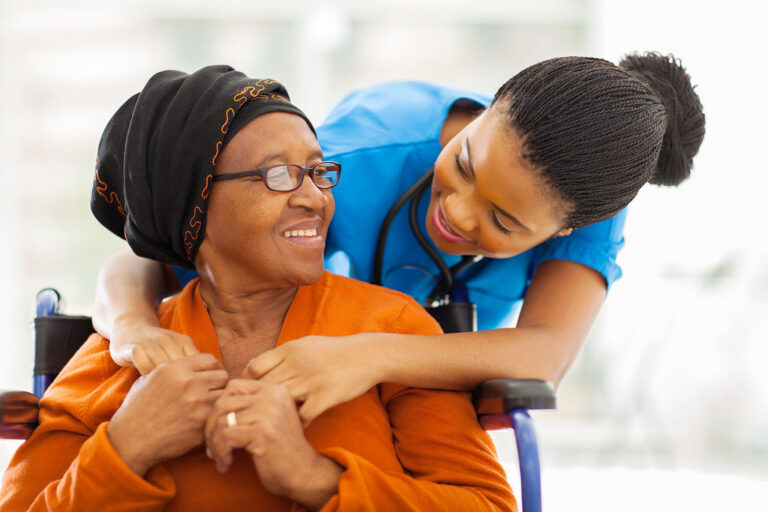 Friendly nurse hugging a happy senior woman patient in a bright clinic
