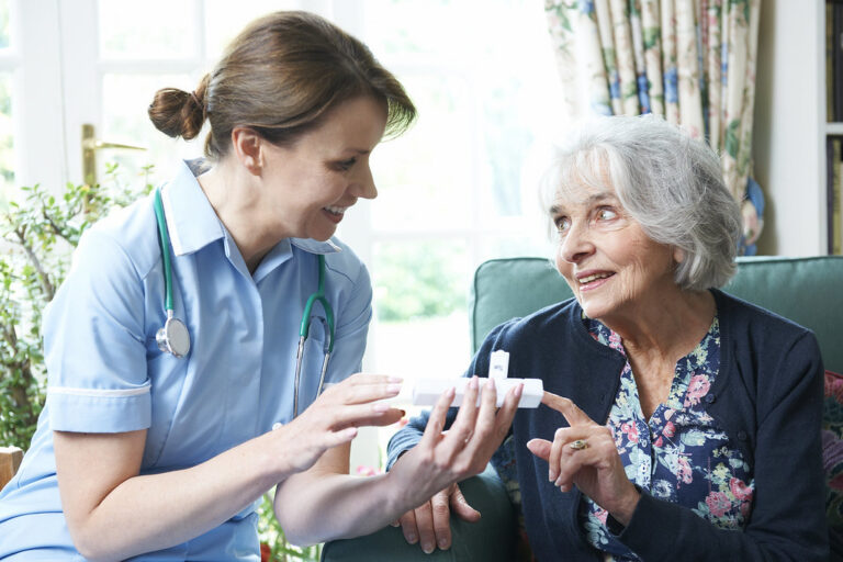 Friendly nurse chatting with a smiling senior woman in a bright living room at home