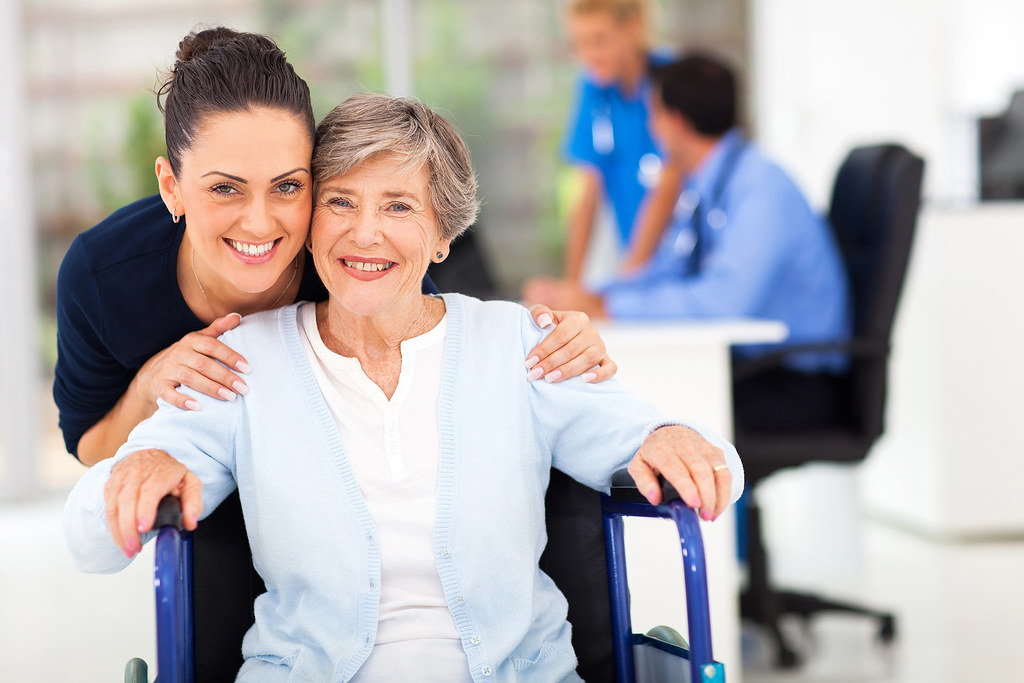 Adult daughter smiling with her senior mother at a bright clinic during a doctor visit