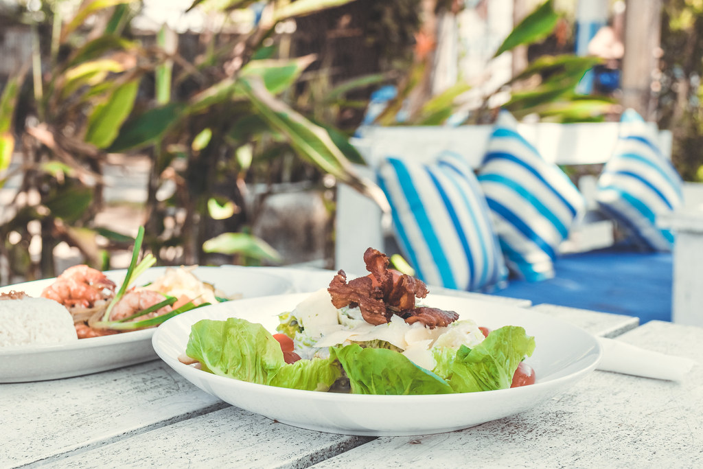 Fresh salad served on a white plate at a bright outdoor cafe table