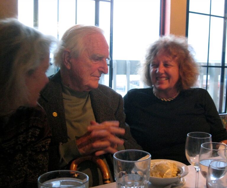 Group of older friends laughing and talking together around a dinner table