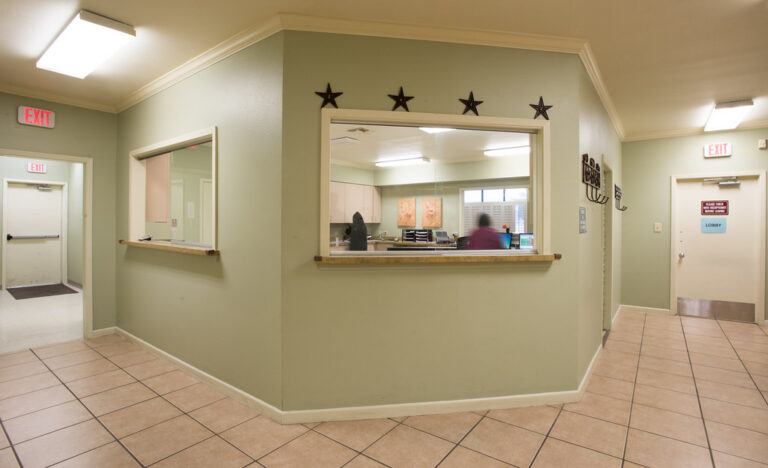 Clean, bright clinic hallway with a reception window and tiled floor