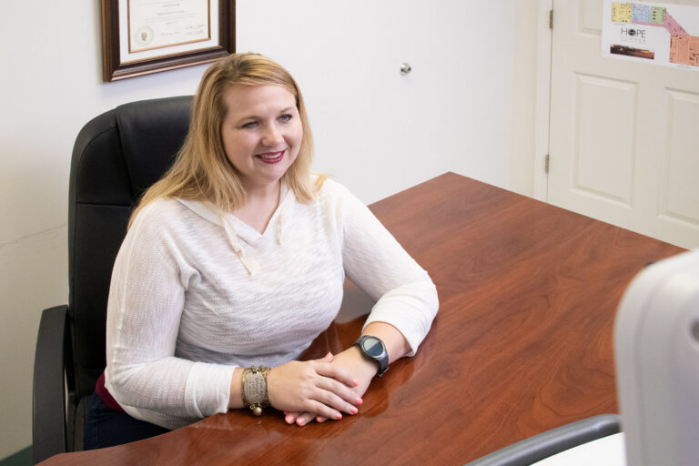 Smiling woman seated at a desk in a bright, welcoming consultation office