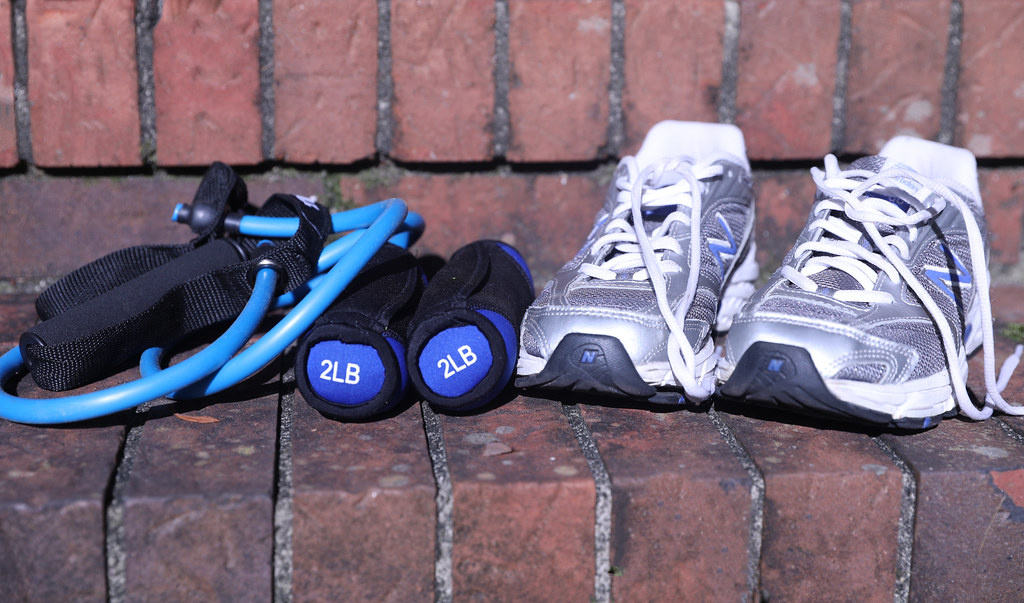 Running shoes, light hand weights and a blue resistance band resting on a brick step