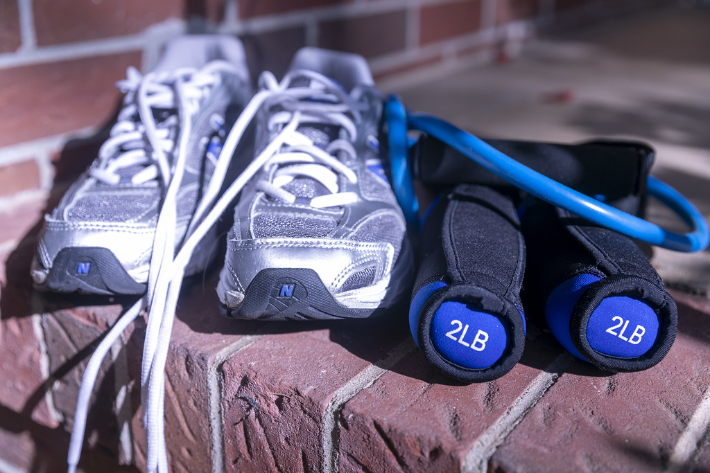 Running shoes, hand weights and a resistance band ready for a workout on a brick step