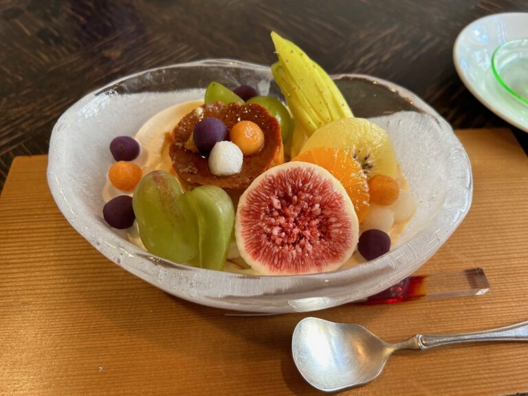 Colorful fresh fruit arranged in a clear glass bowl on a wooden table
