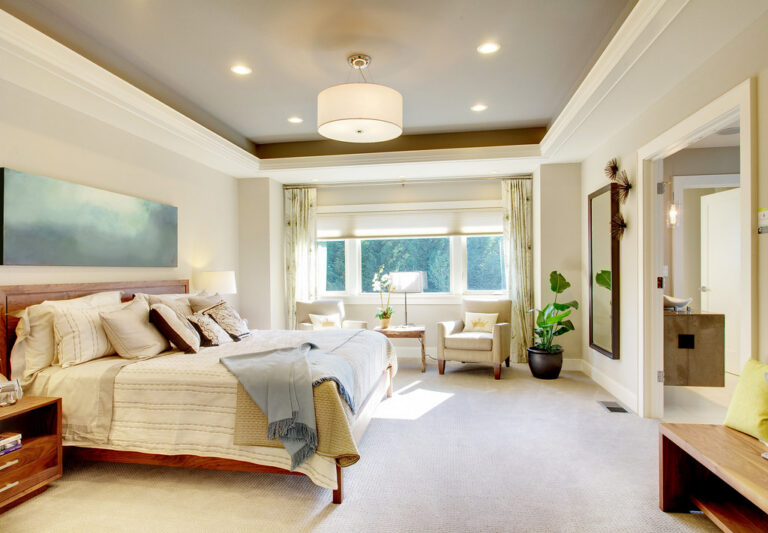 Bright, tidy bedroom with a neatly made bed and soft daylight from large windows