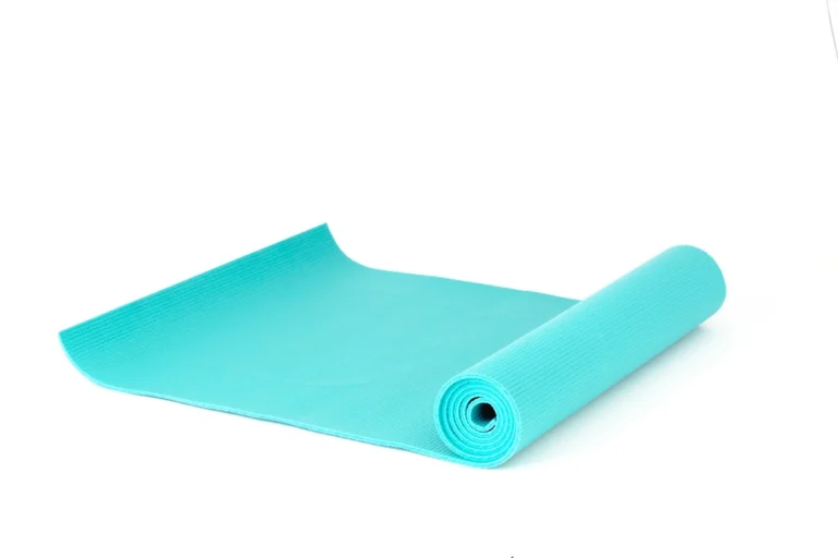 Teal yoga mat partly unrolled on a clean white background