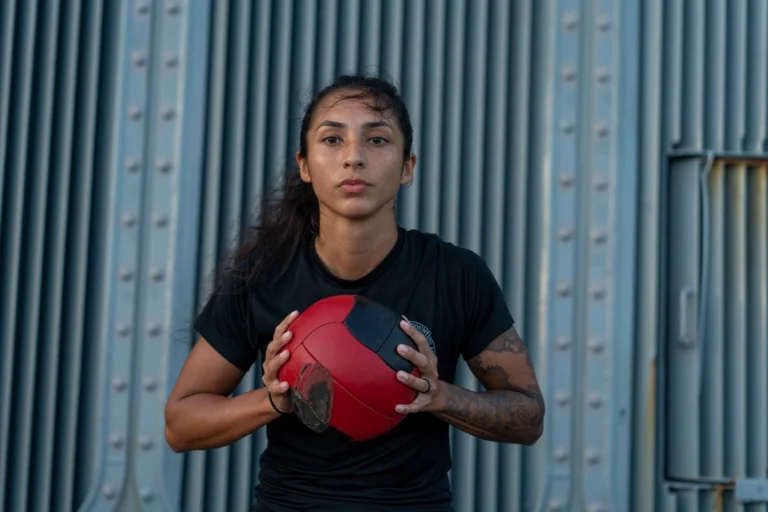 Woman in a black t-shirt holding a red exercise ball, ready for a strength workout