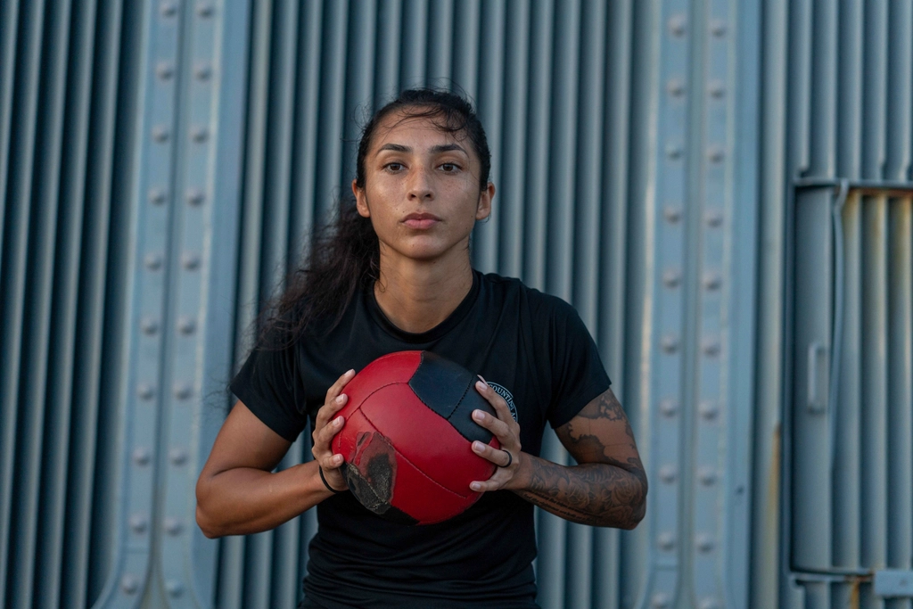 Woman in a black t-shirt holding a red exercise ball, ready for a strength workout