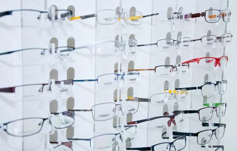 Rows of colorful eyeglass frames displayed on a bright white wall in an optical shop