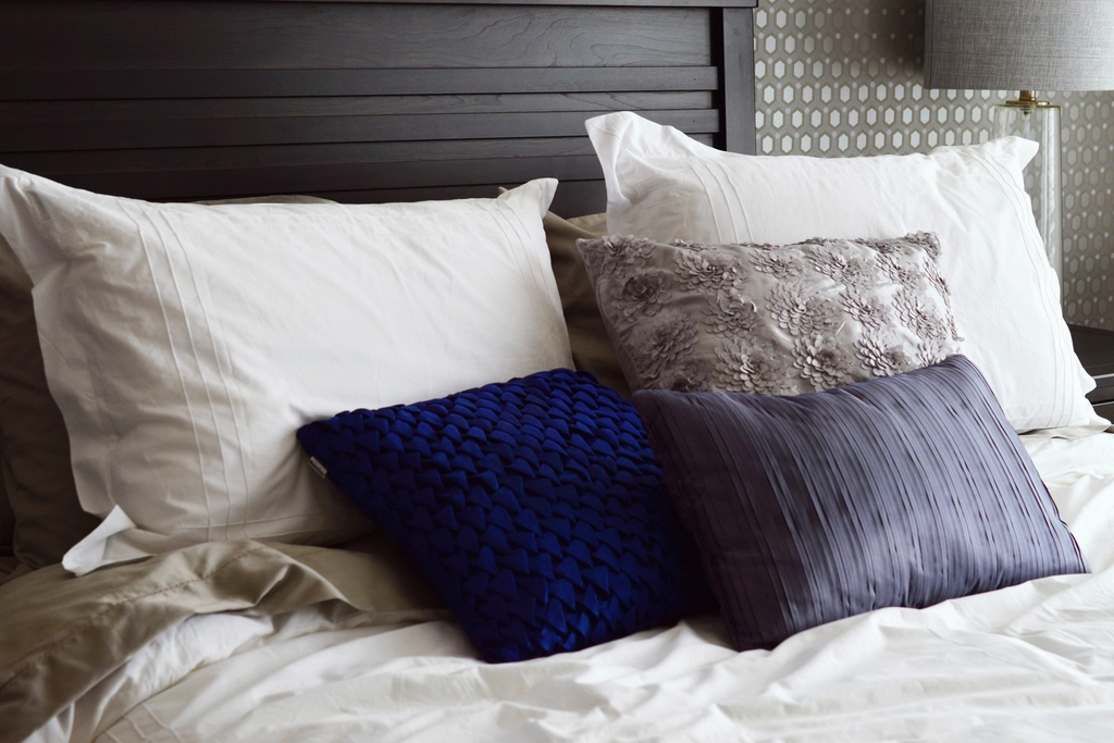 Soft white and navy pillows arranged on a freshly made bed