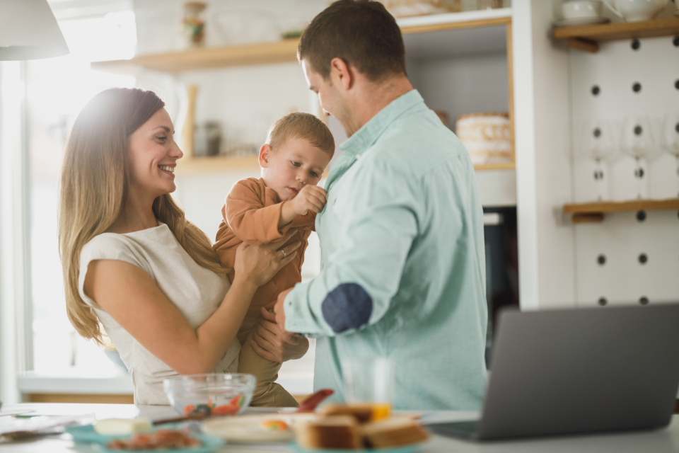 Smiling mother and father holding their baby in a bright home kitchen