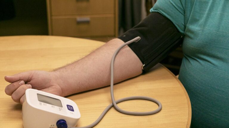 Adult checking blood pressure at home with an upper-arm monitor